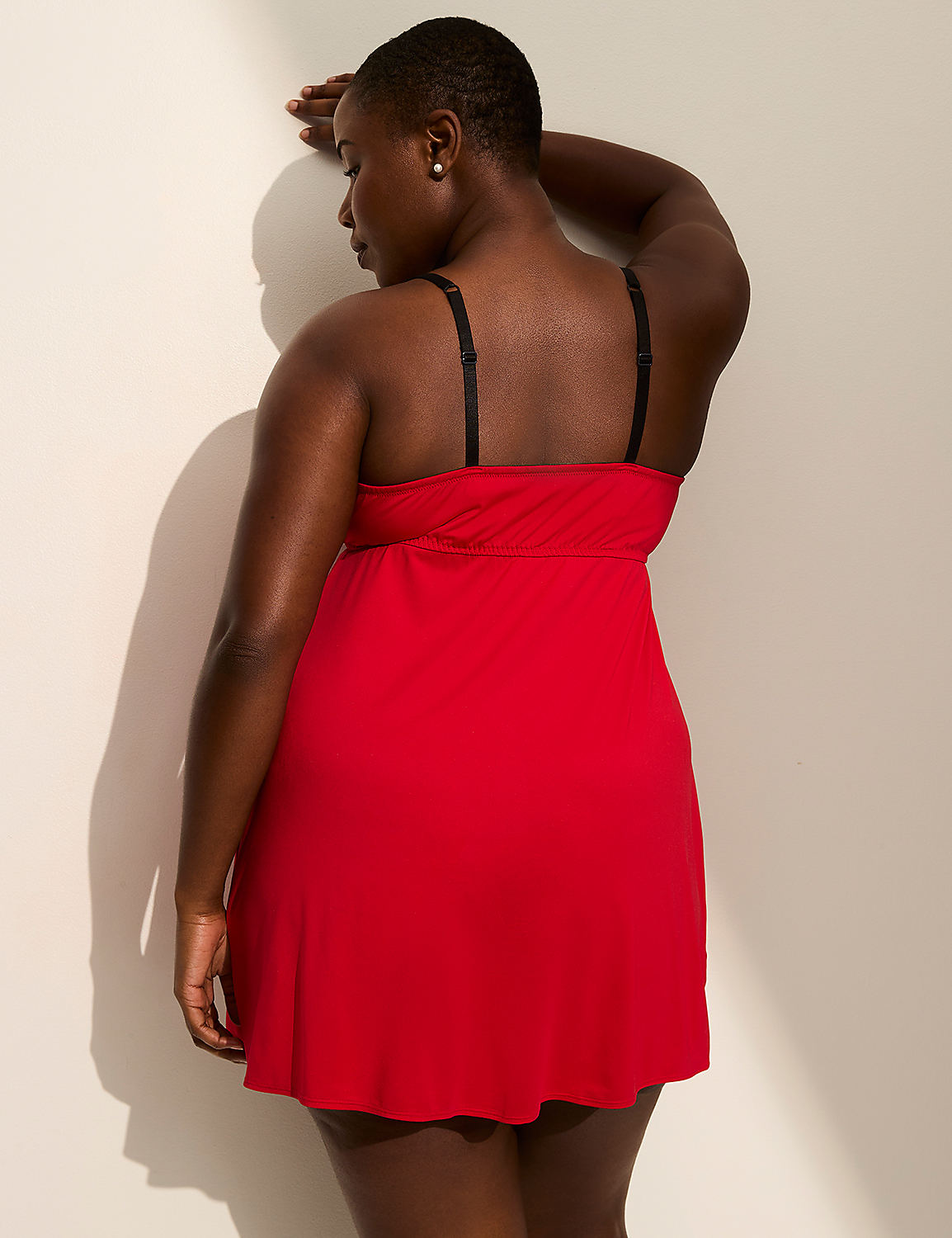 A woman in a red nightgown leans against a wall, with a shadow cast on the wall behind her. Product Image 2