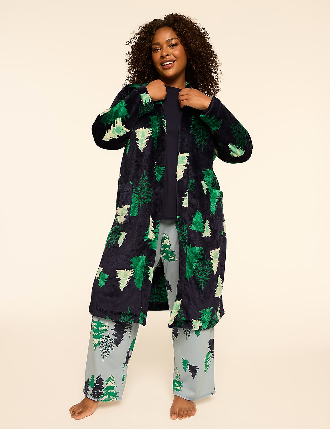 A woman in a festive tree-patterned robe and pajama pants stands against a plain, light-colored background. Product Image 3