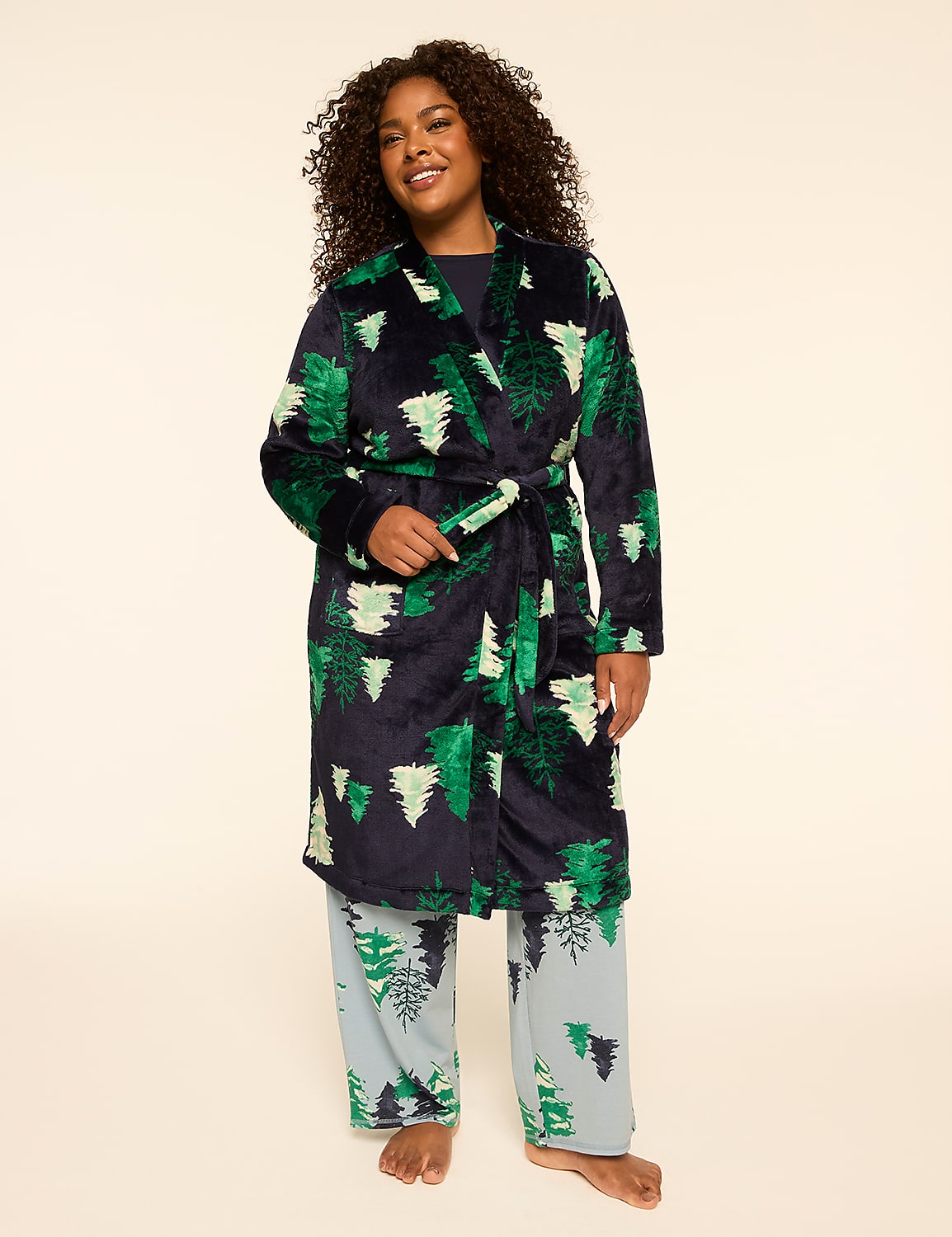 A woman in a festive green tree-patterned robe and matching pajama pants stands against a plain, light-colored background. Product Image 1