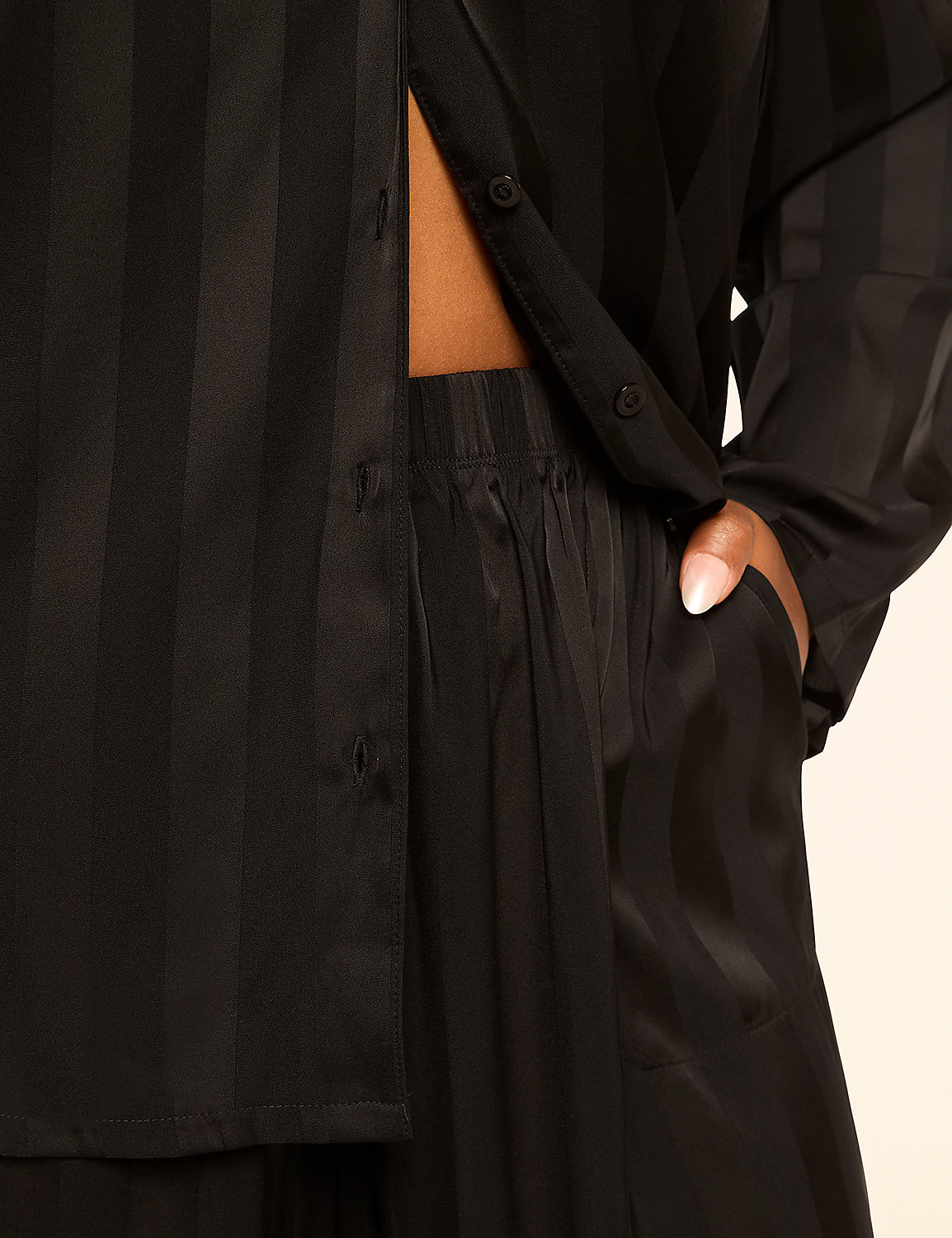 A close-up of a person wearing black striped pajamas with a hand in their pocket, set against a plain, light-colored background. Product Image 3