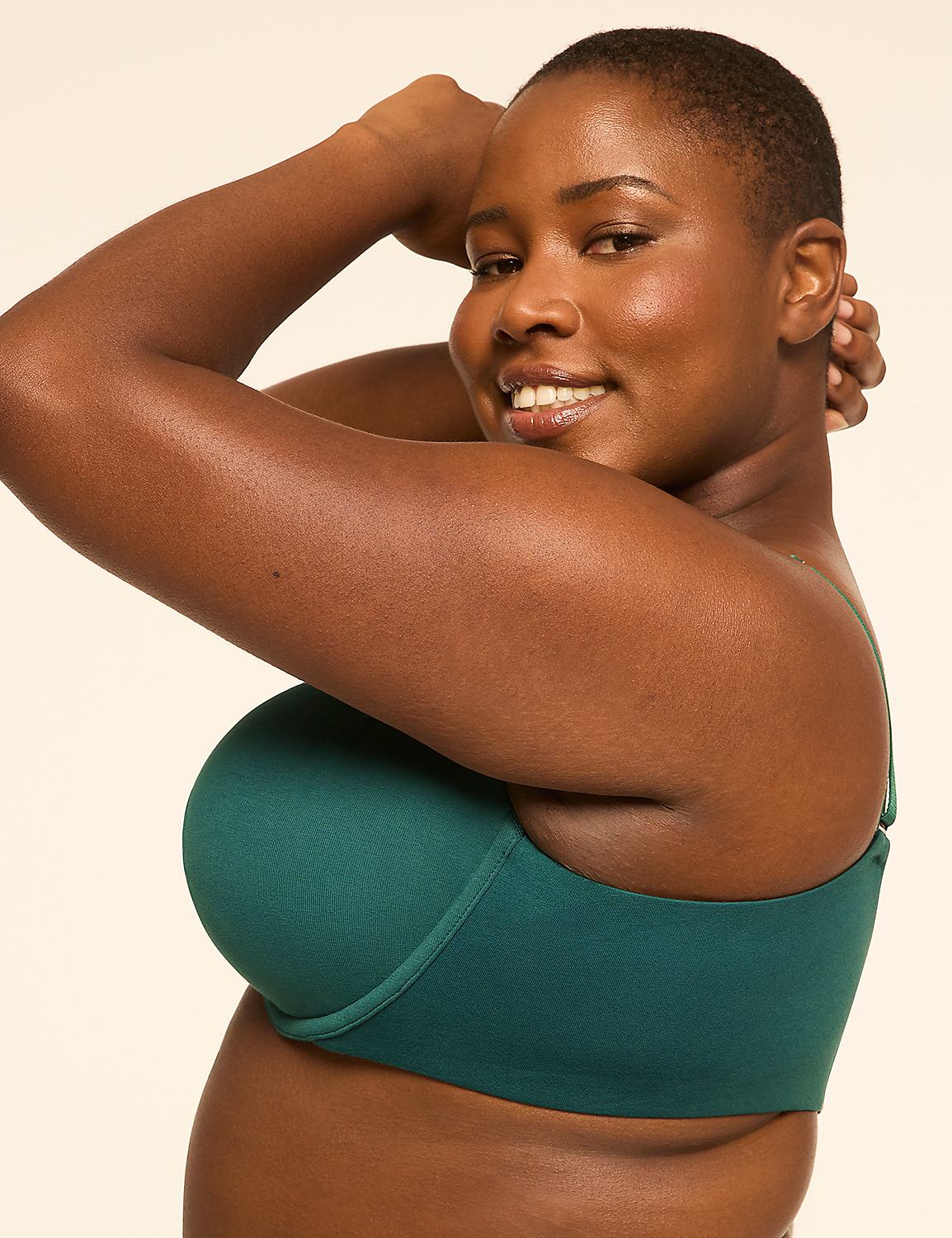 A woman in a teal bra smiles as she poses with her arms behind her head against a plain, light background. Product Image 3