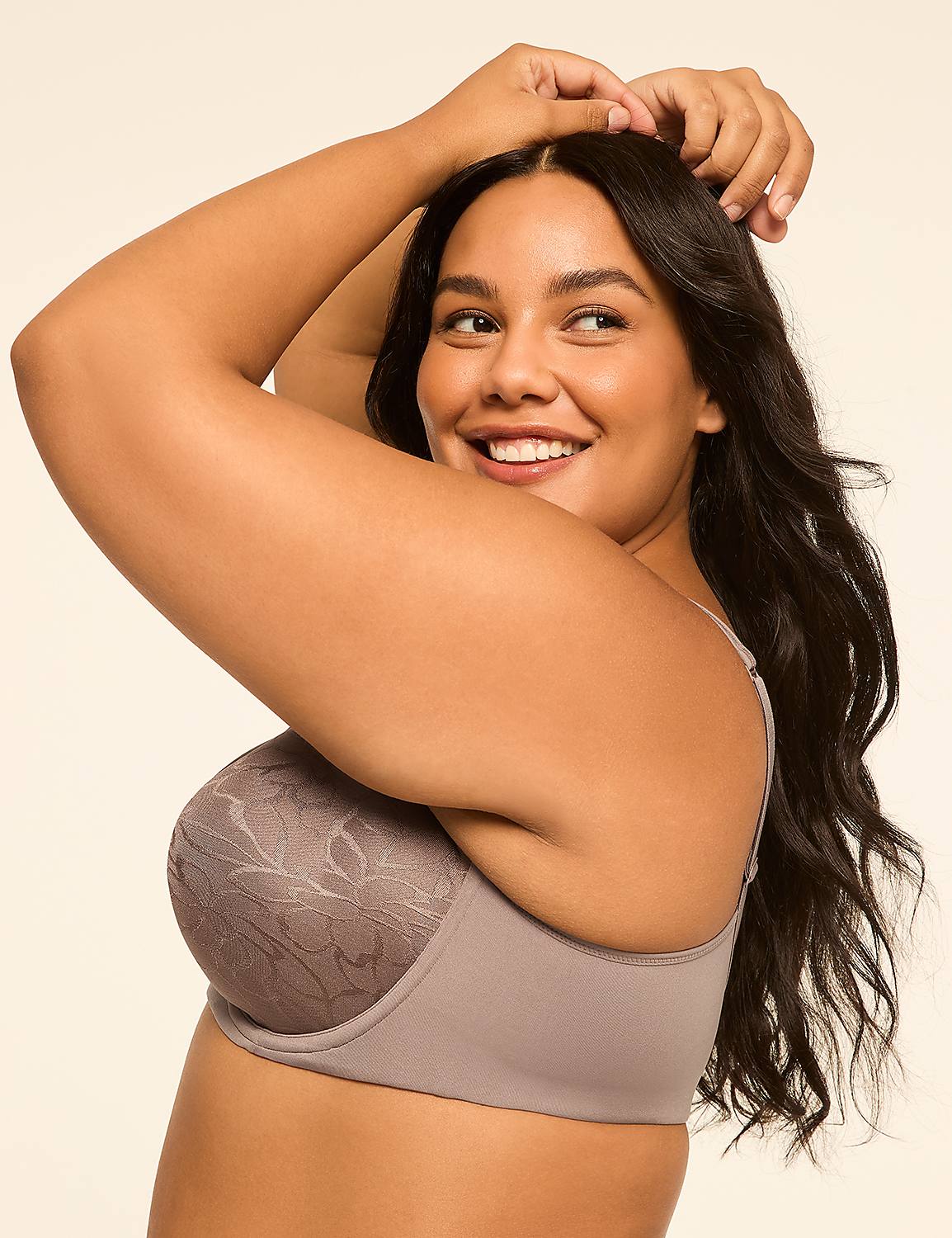 A smiling woman with dark hair poses with her arms behind her head in front of a plain, light-colored background. Product Image 3