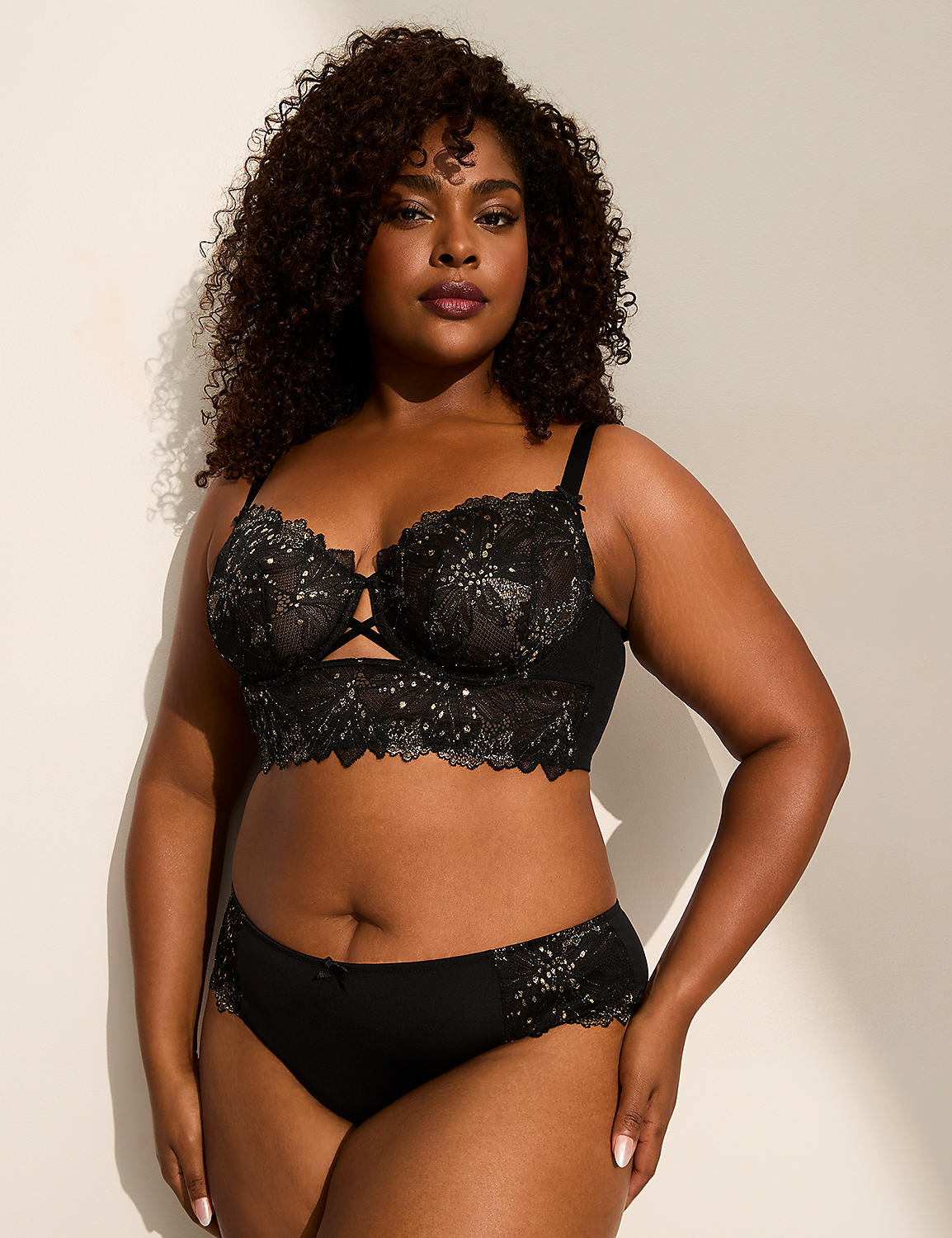 A woman with curly dark hair poses in black lace lingerie against a plain, light-colored background. Product Image 4