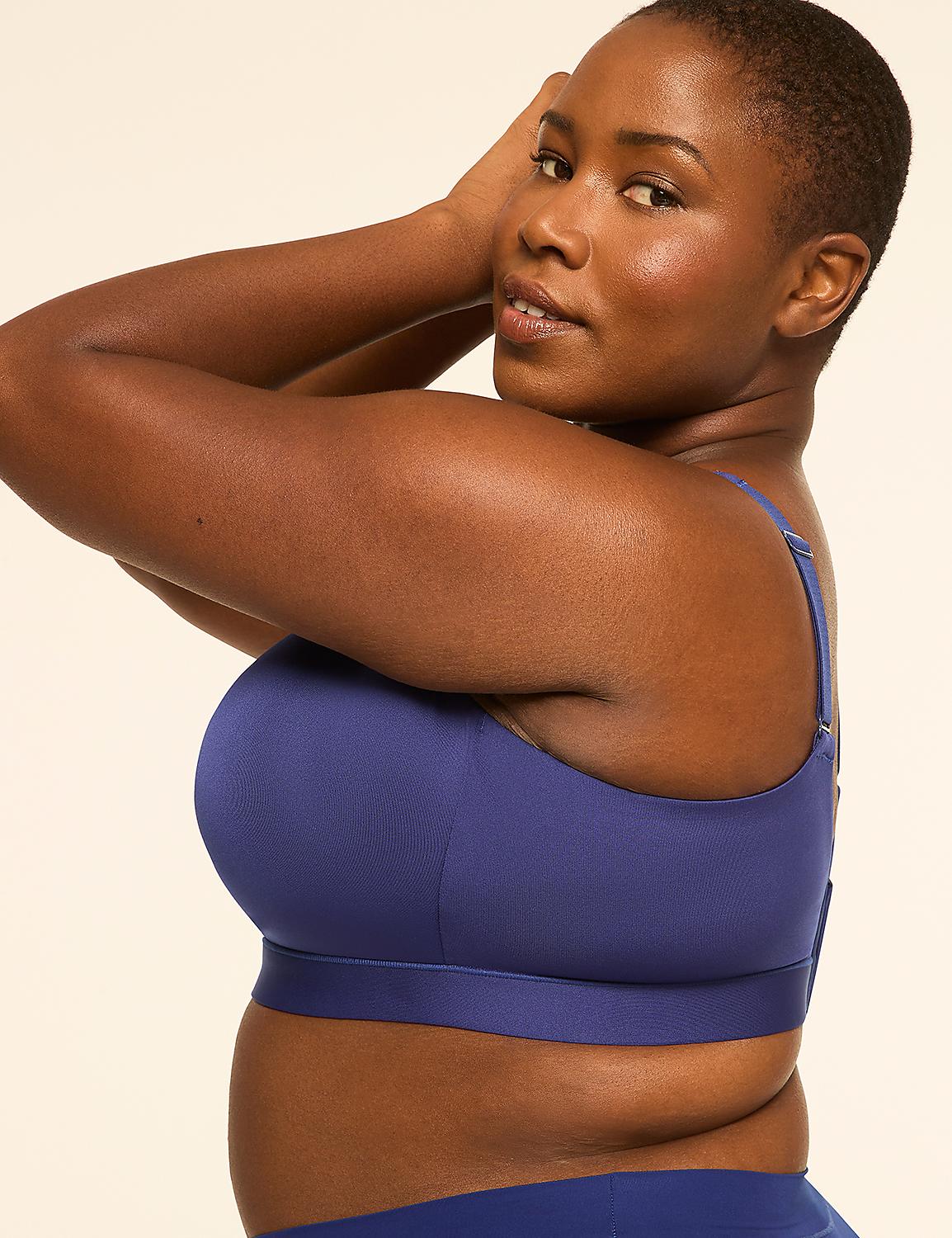 A woman in a blue sports bra poses with her arms behind her head against a plain, light-colored background. Product Image 3