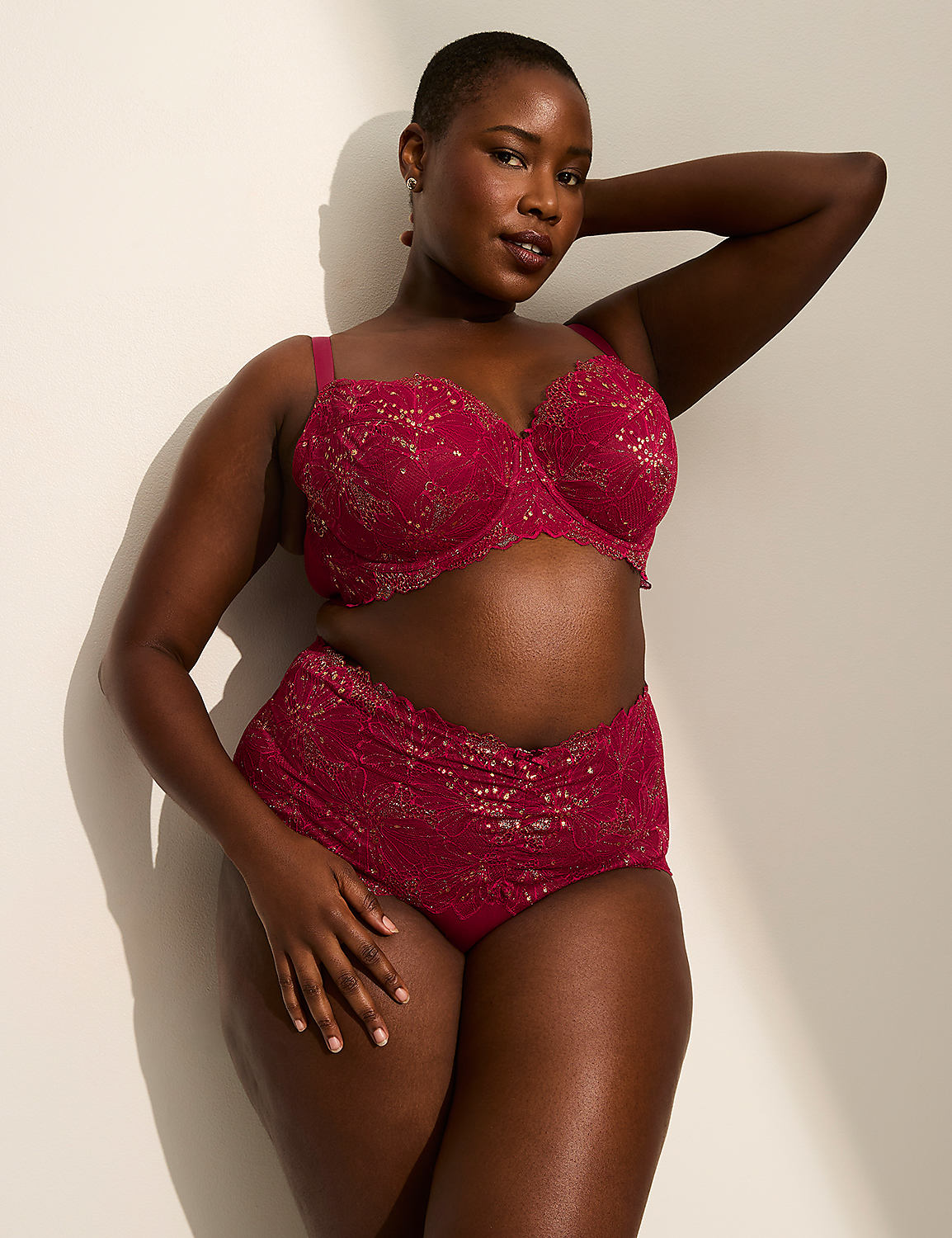A woman in a red lace bra and high-waisted underwear poses against a plain, light-colored wall with soft shadows. Product Image 4