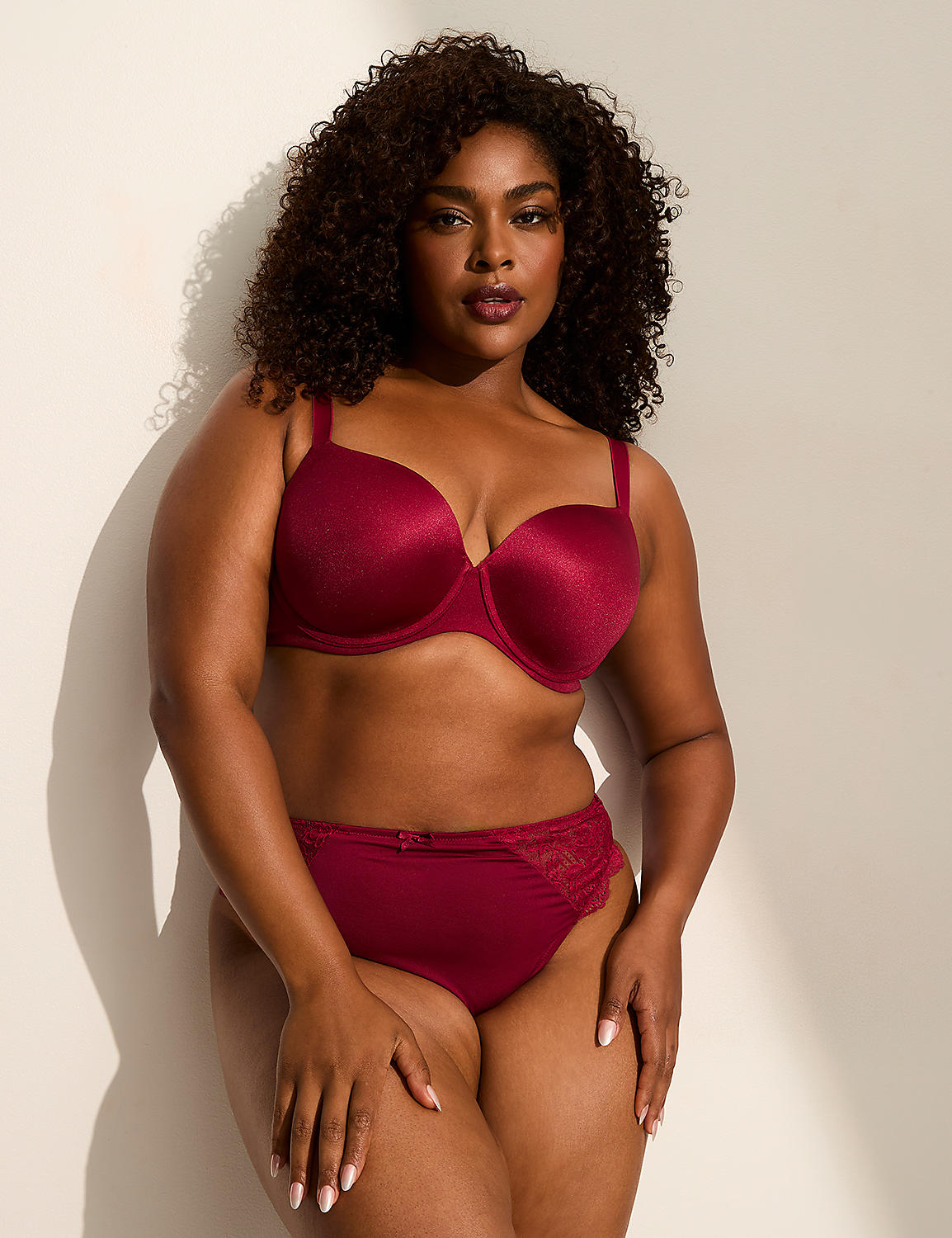 A woman in a burgundy bra and matching underwear stands against a plain, light-colored wall with shadows. Product Image 3
