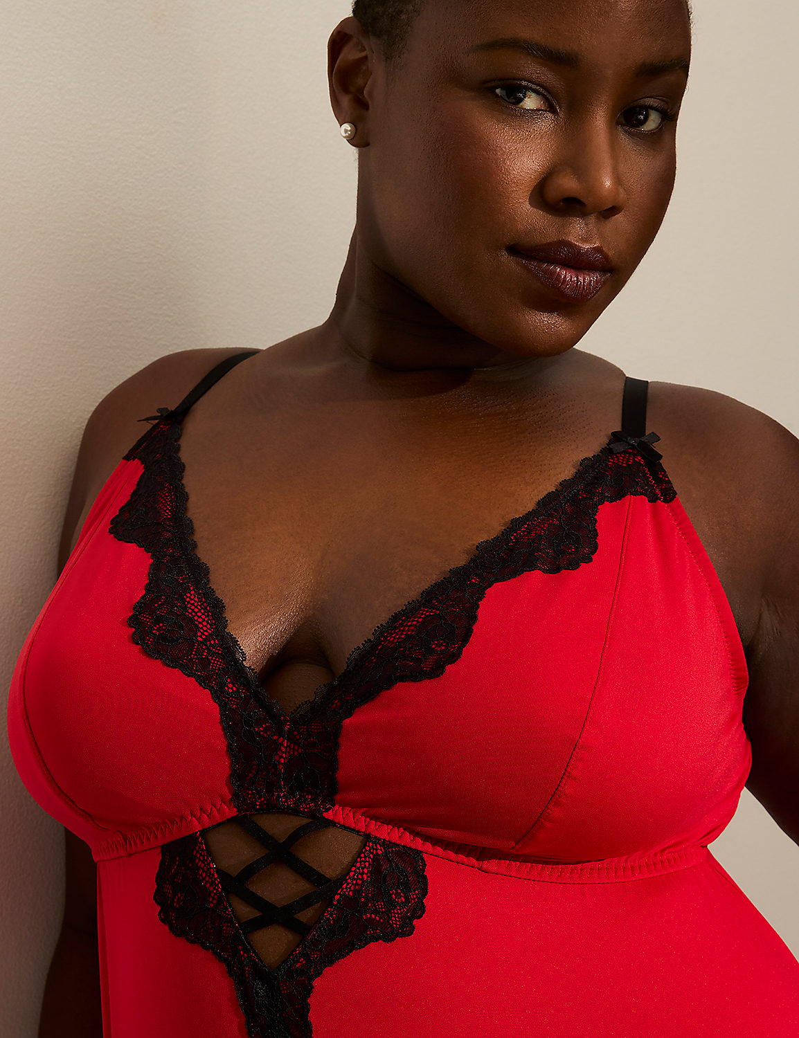 A woman in a red and black lace chemise leans against a plain, light-colored wall. Product Image 3