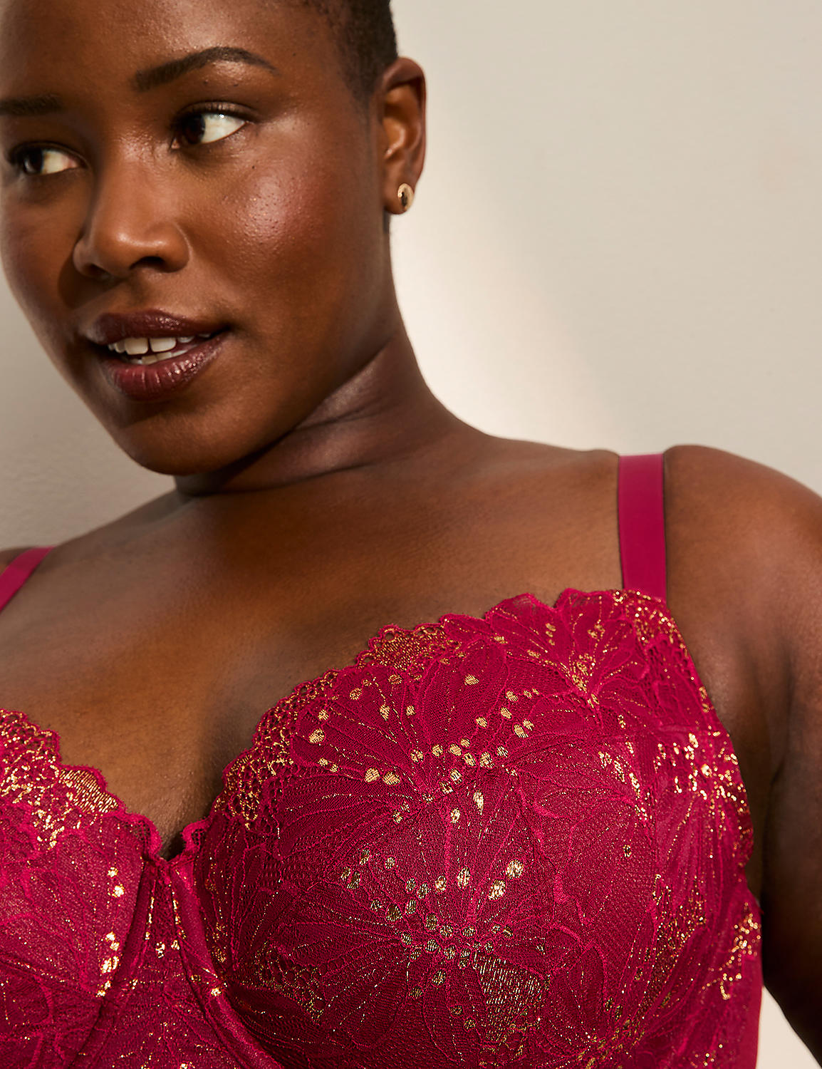 A woman with dark skin and short hair wears a vibrant pink lace bra with gold accents, set against a soft, neutral background. Product Image 2