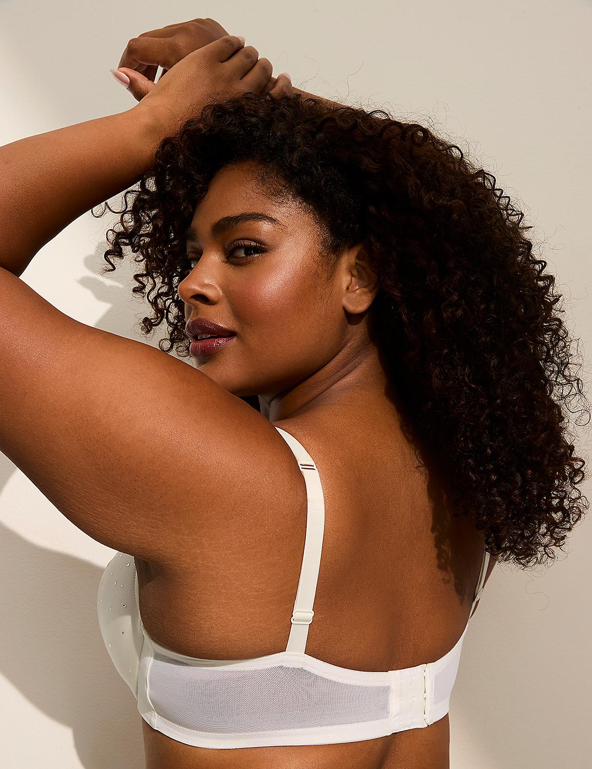 A woman with curly dark hair poses with her arms behind her head, wearing a white bra against a plain, light-colored background. Product Image 3