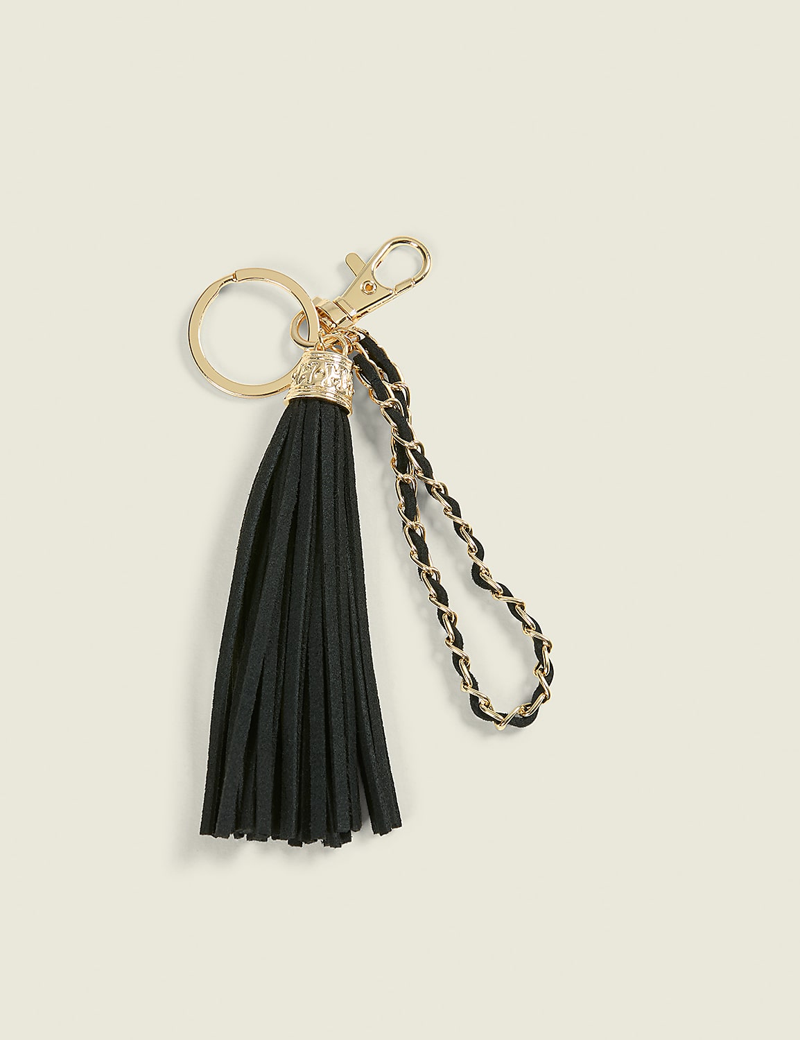 A black tassel keychain with gold hardware and a braided chain strap rests on a light beige background. Product Image 1