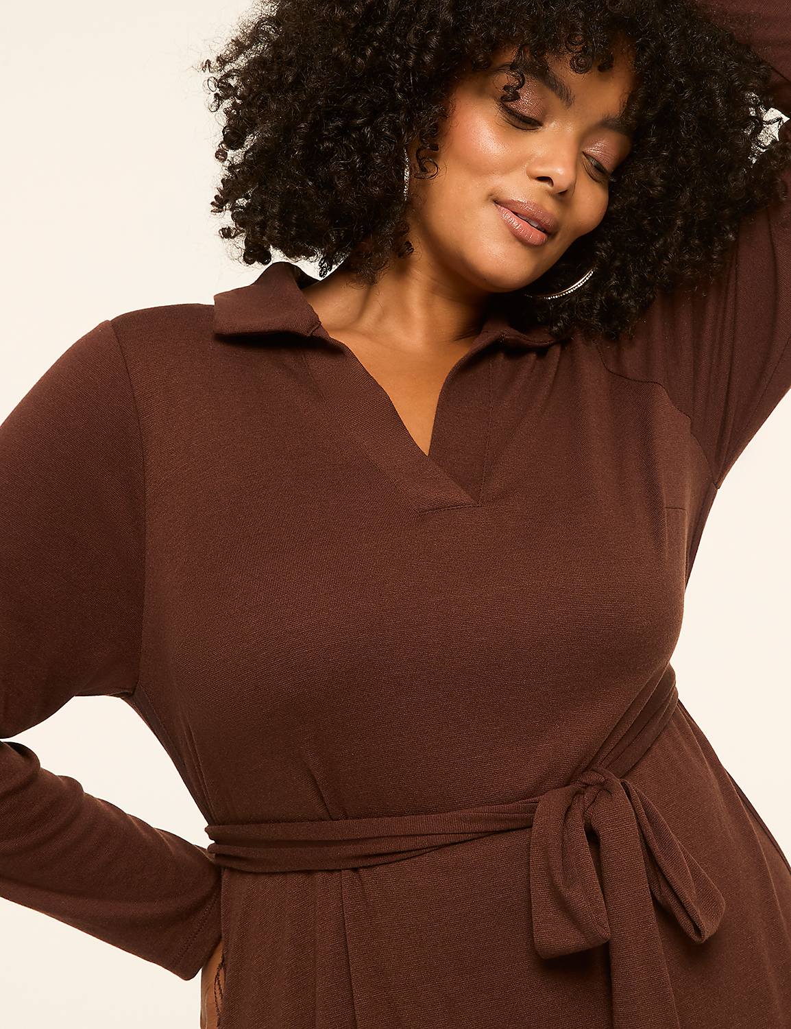 A woman with curly hair in a brown collared dress with a tie waist poses against a plain, light background. Product Image 3