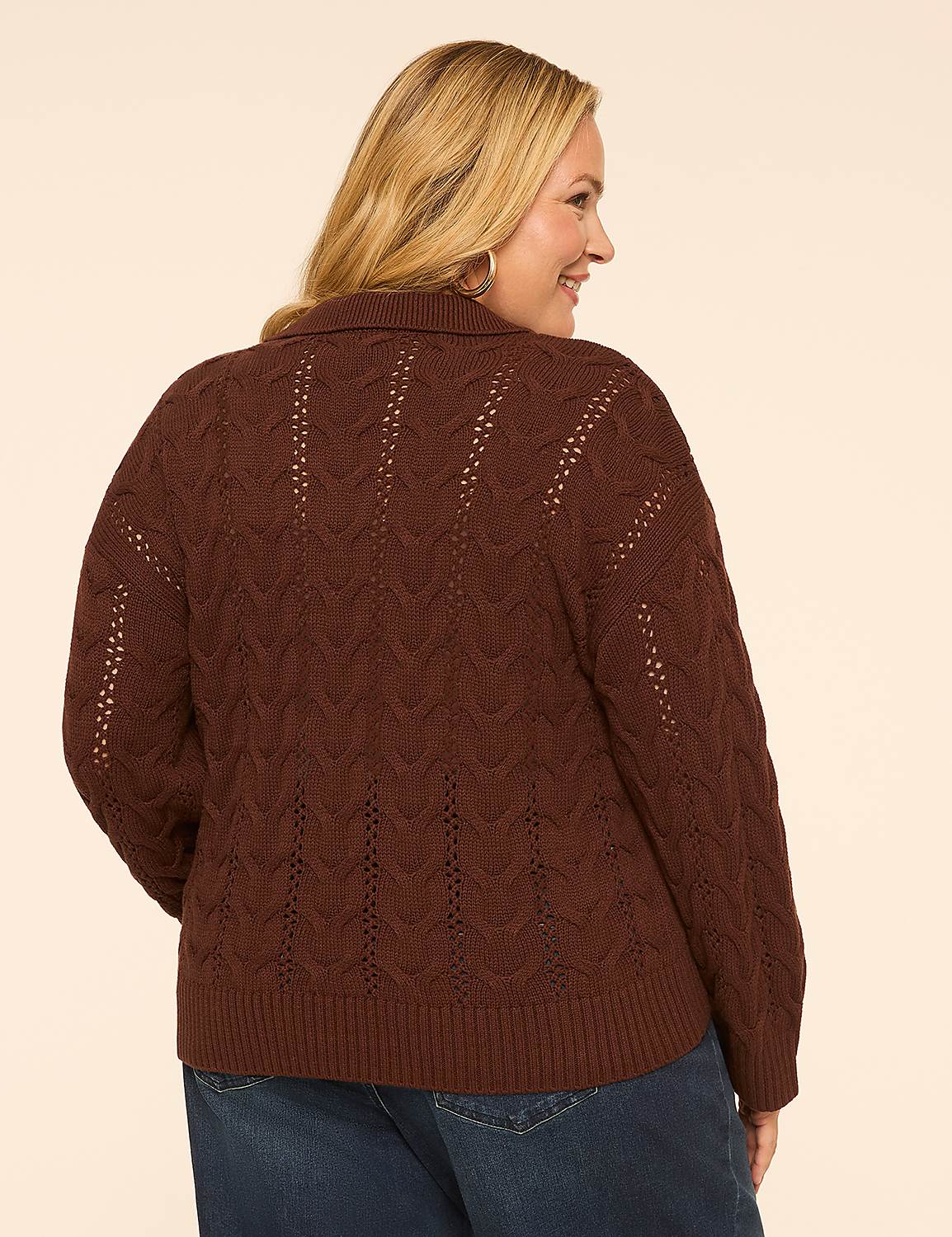 A woman in a brown cable-knit sweater and blue jeans stands against a plain, light-colored background. Product Image 2
