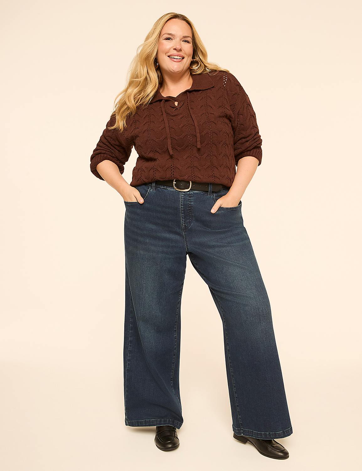A woman in a brown cable-knit sweater and wide-leg jeans stands against a plain, light-colored background. Product Image 3