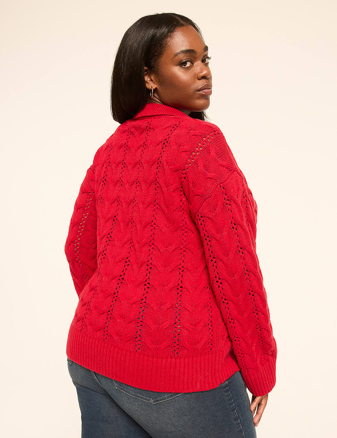 A woman in a red cable-knit sweater and blue jeans stands against a plain, light-colored background. Product Image 2