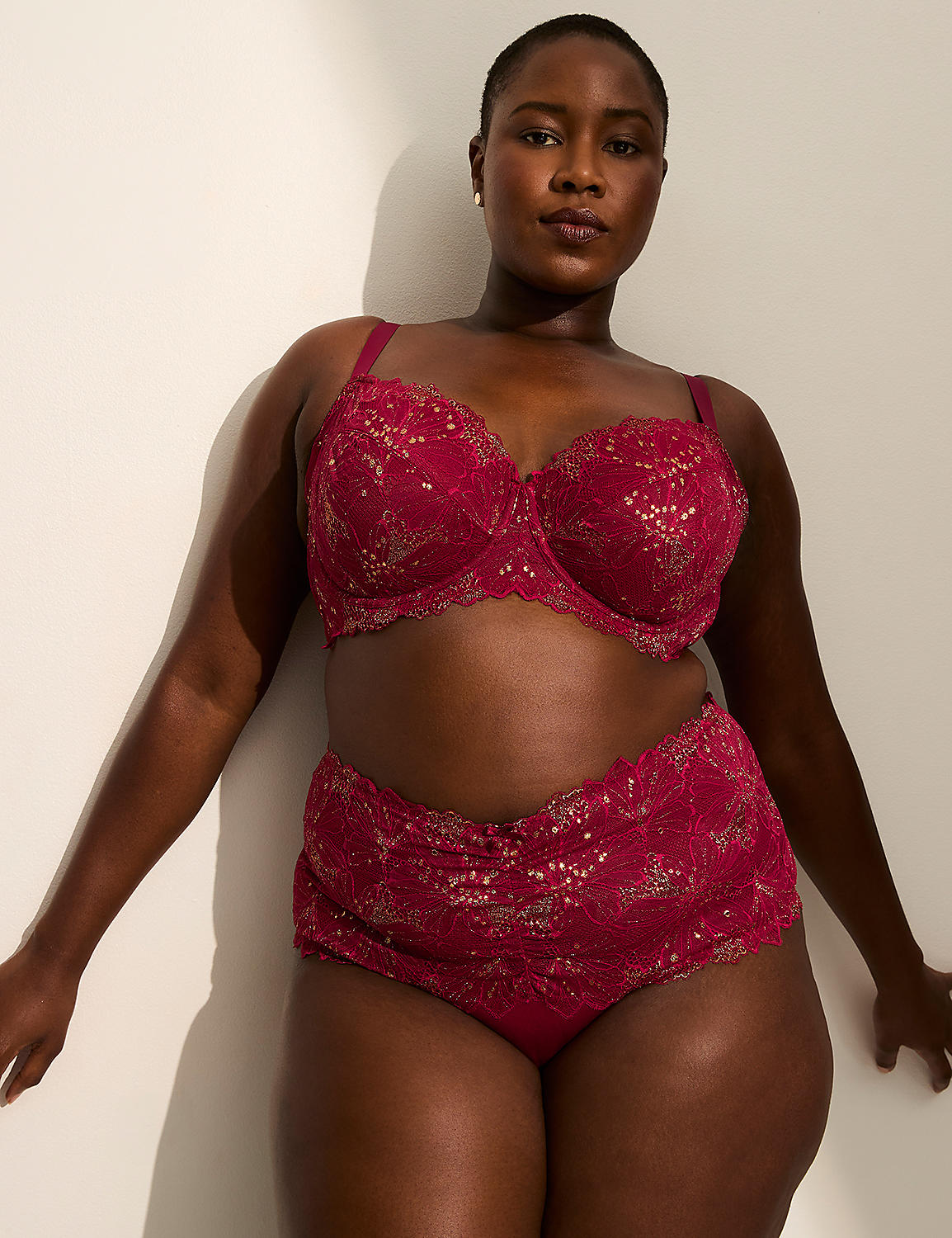 A woman in a red lace bra and underwear stands against a white wall with soft lighting. Product Image 3