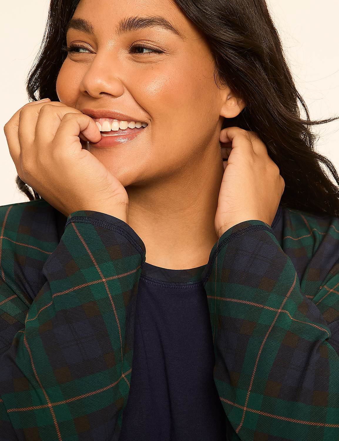 A smiling woman in a plaid shirt rests her hands on her face against a plain background. Product Image 4