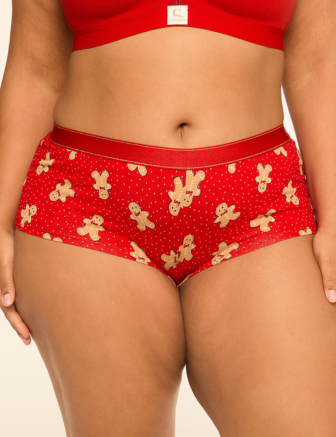 A person wears red polka dot underwear with gingerbread men patterns in the foreground, against a plain background. Product Image 1