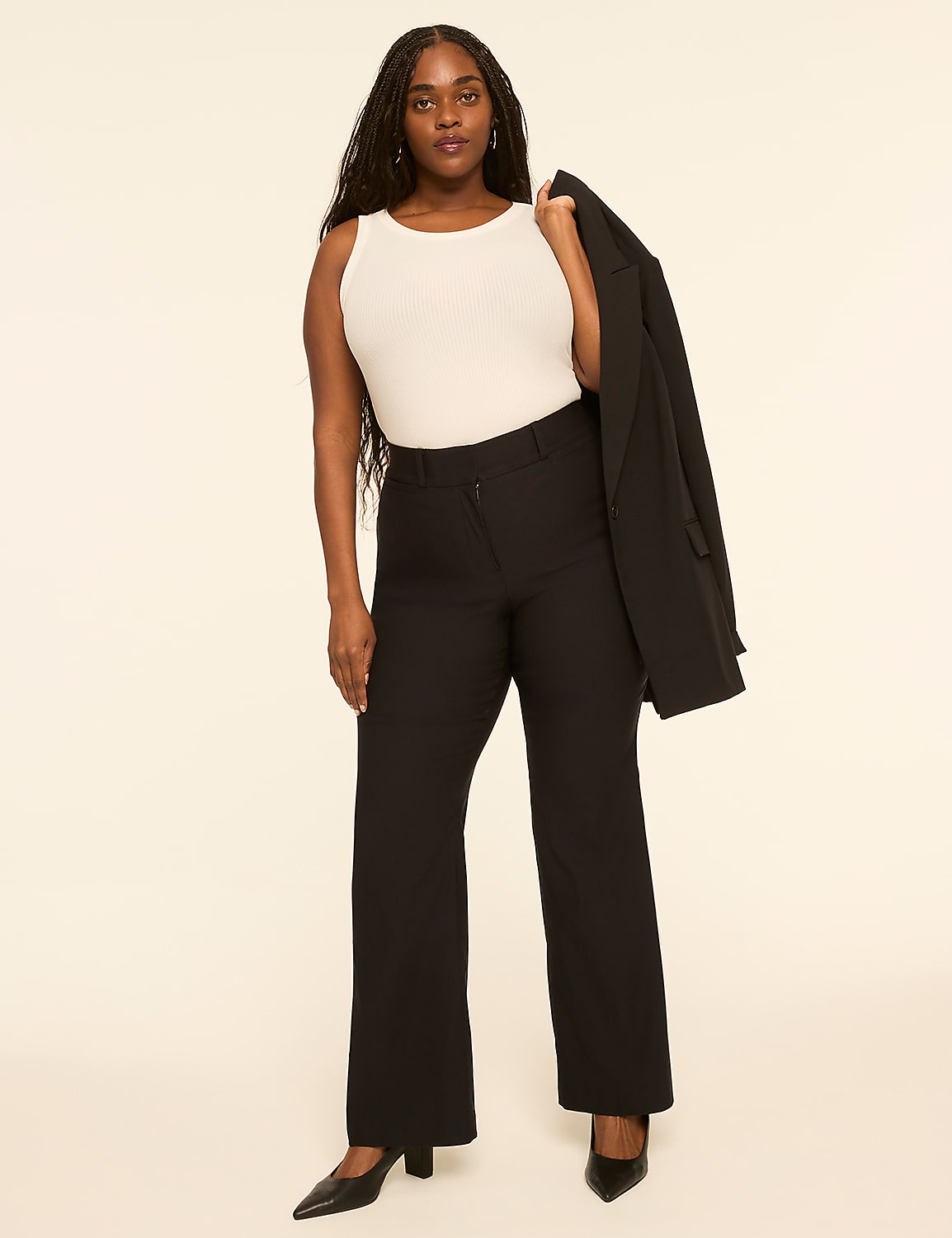 A woman in a white tank top and black pants stands against a plain, light-colored background, holding a black blazer over her shoulder. Product Image 3
