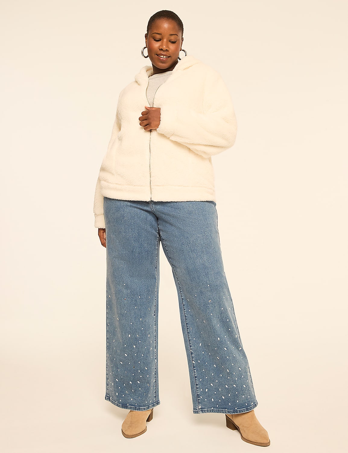 A woman in a cream-colored fuzzy jacket and embellished jeans stands against a plain, light background. Product Image 3