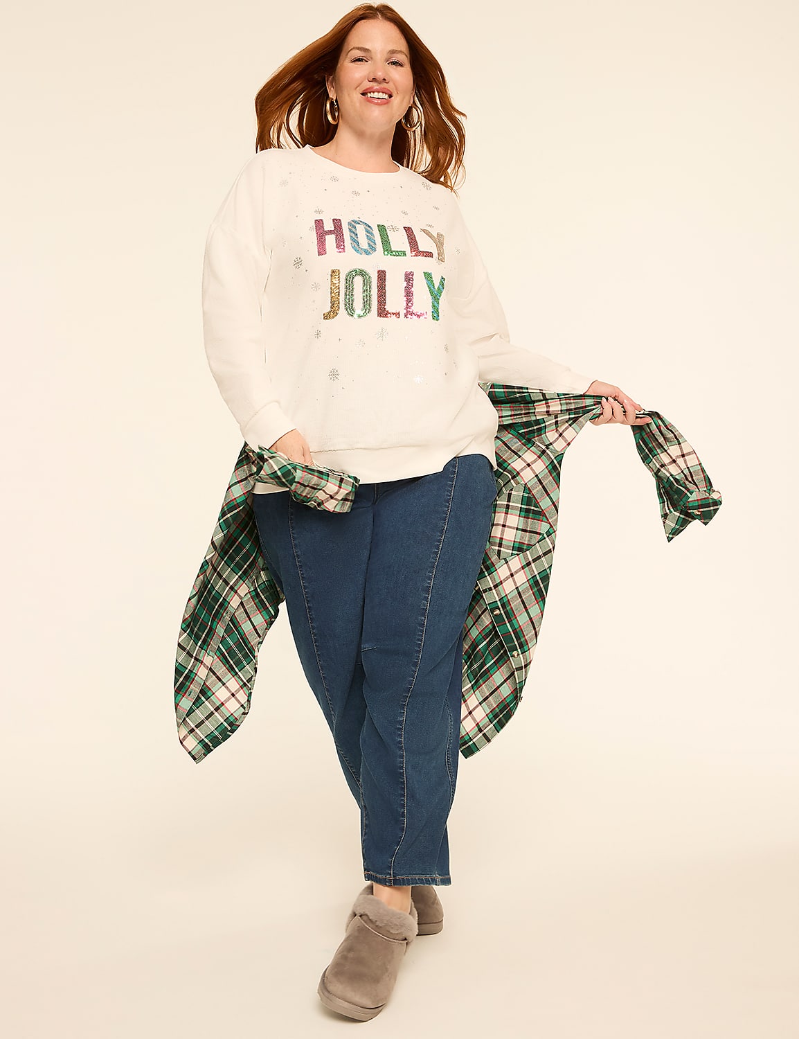 A woman in a white "HOLLY JOLLY" sweater and jeans poses against a plain background, with a green plaid shirt draped over her shoulders. Product Image 3