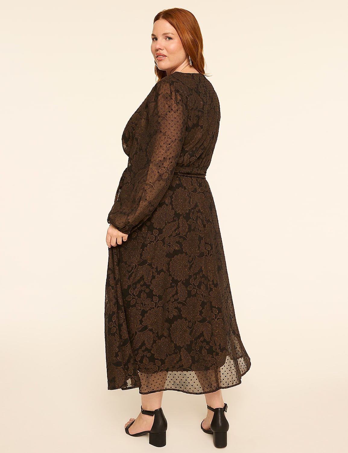 A woman in a long, patterned dress stands against a plain, light brown background. Product Image 2