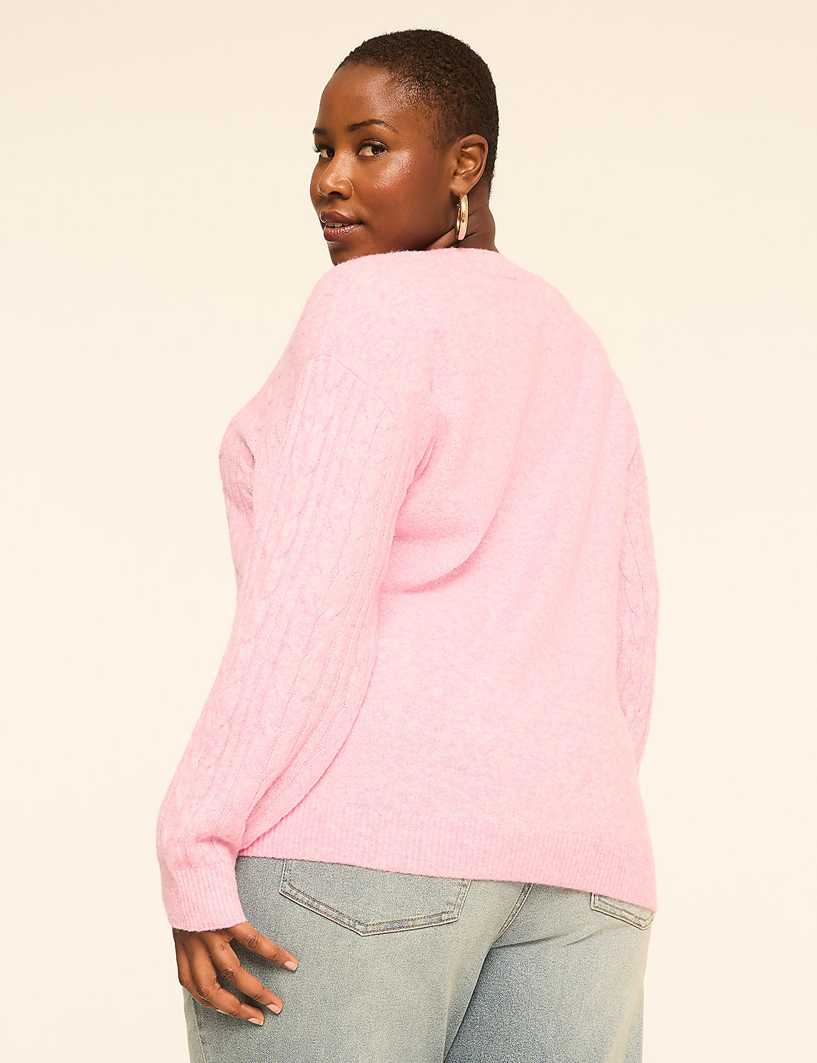 A woman in a pink cable-knit sweater and light-wash jeans poses against a plain, light-colored background. Product Image 2