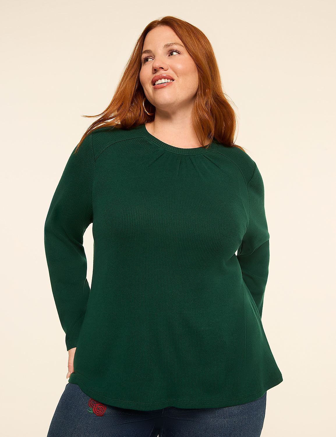 A woman with red hair smiles as she poses in a green waffle-knit top and jeans against a plain, light-colored background. Product Image 1