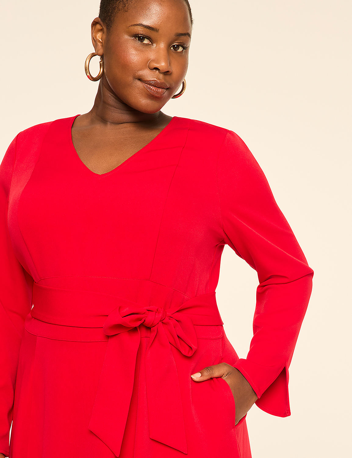 A woman in a red dress with a tie waist stands against a plain, light-colored background. Product Image 3