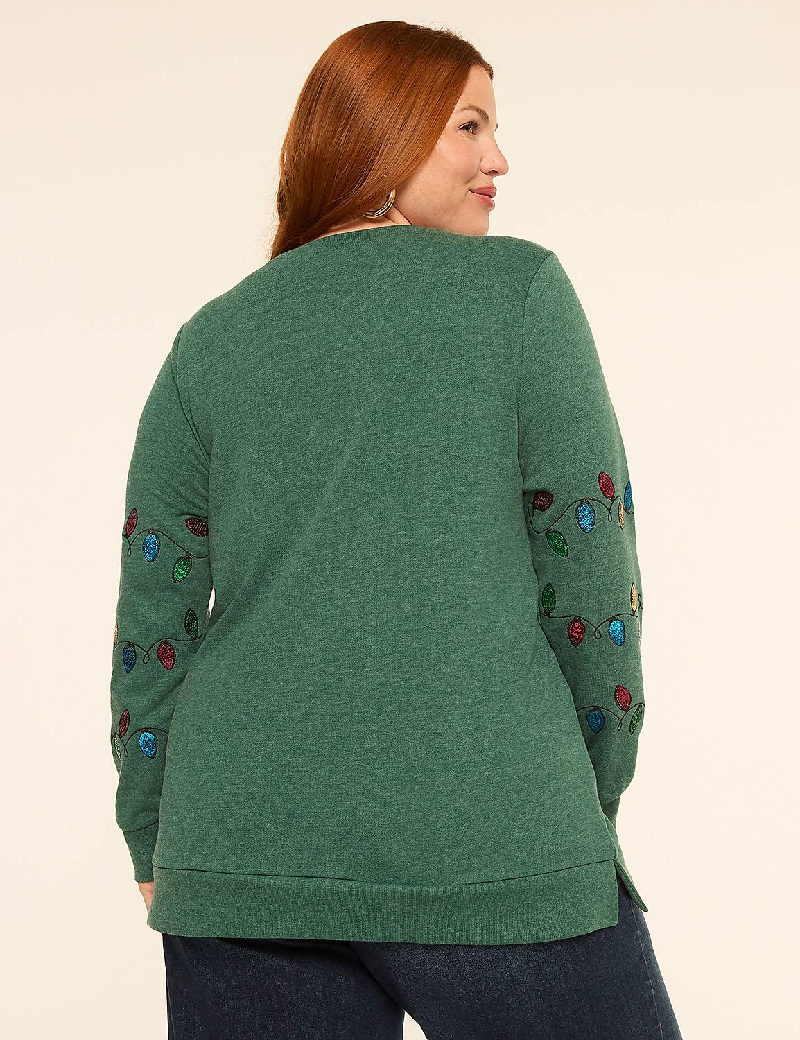 A woman with red hair wearing a green sweatshirt with Christmas lights on the sleeves stands against a plain, light-colored background. Product Image 2