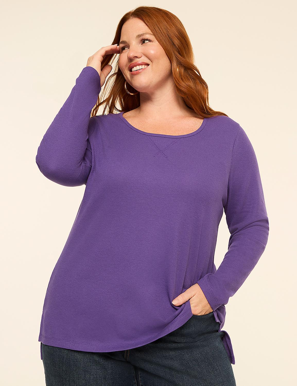 A smiling woman with red hair in a purple long-sleeved shirt and jeans poses against a plain, light-colored background. Product Image 1