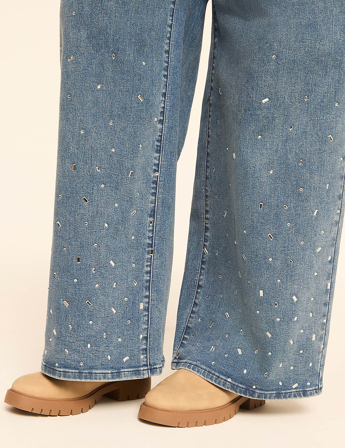 Light-wash denim jeans adorned with scattered rhinestones are worn with tan platform boots against a plain, light-colored background. Product Image 3