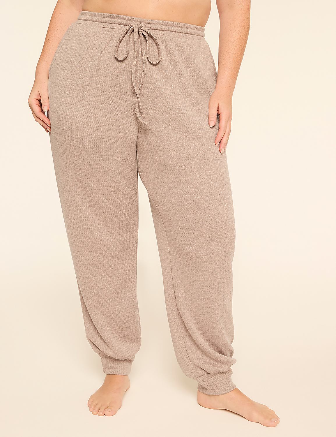 A person stands in the foreground wearing beige waffle-knit sweatpants with a drawstring, against a plain, light-colored background. Product Image 1