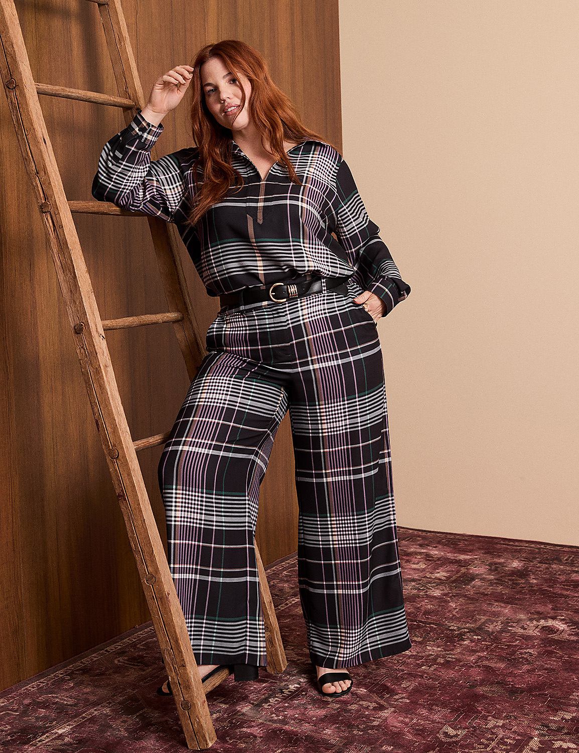 A woman in a plaid outfit leans against a wooden ladder in front of a warm-toned wall and a patterned rug. Product Image 1