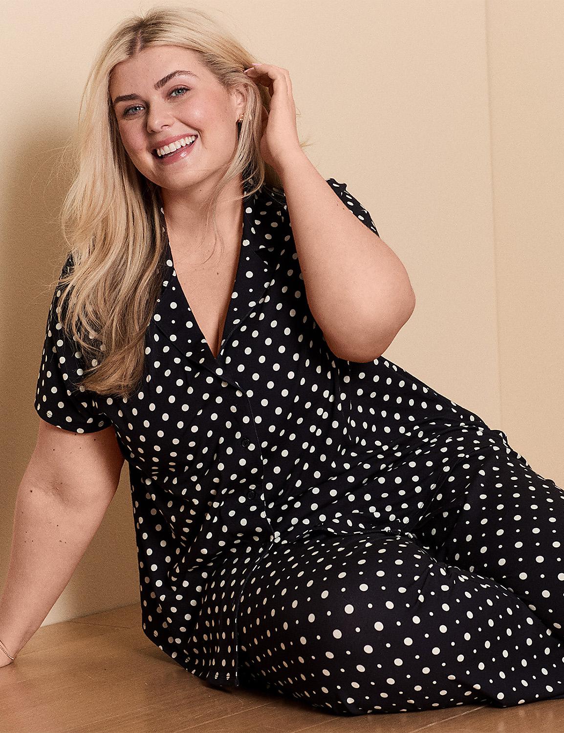 A smiling woman in a black and white polka dot outfit sits on a wooden floor with a plain beige wall behind her. Product Image 1