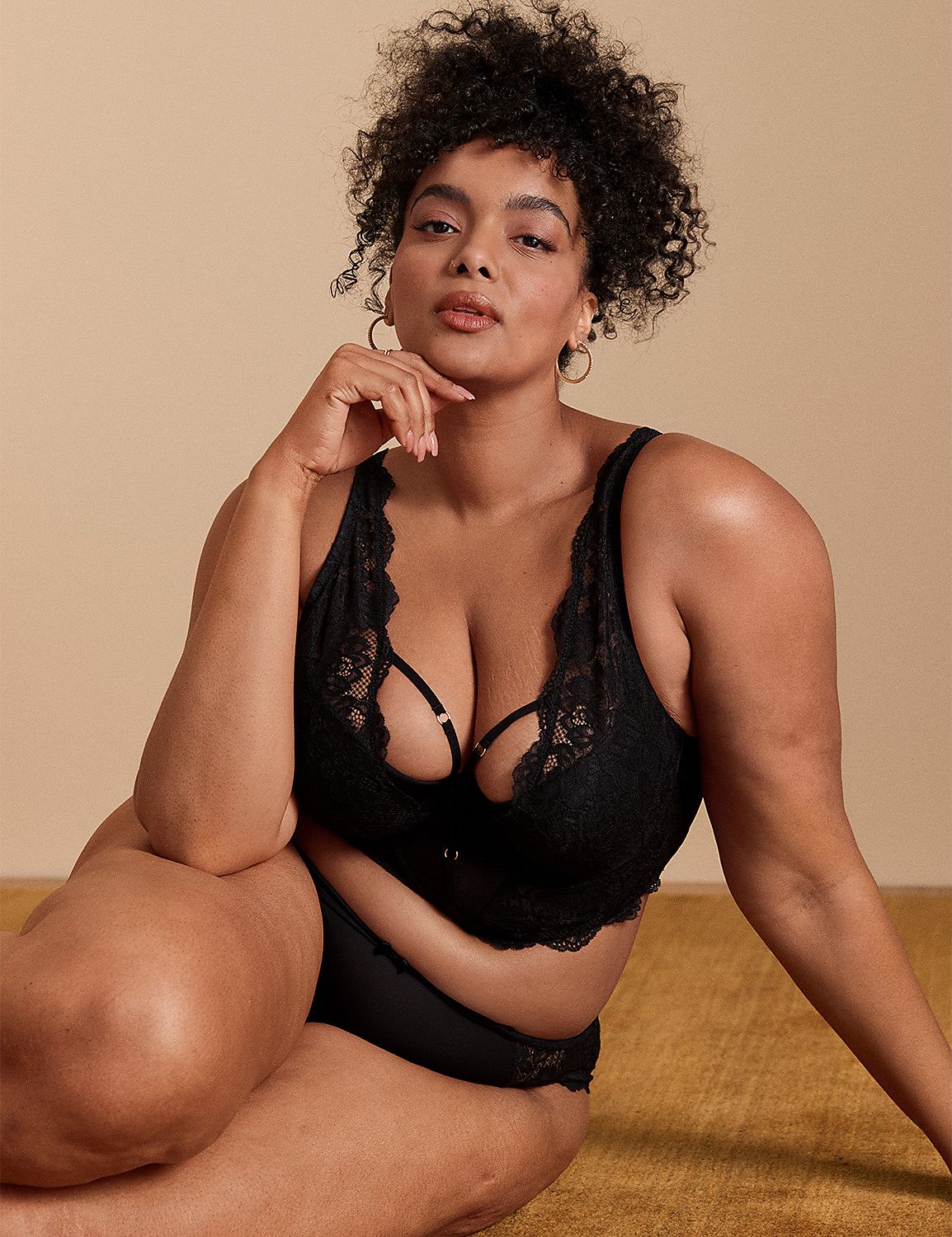 A woman in black lingerie poses on a textured yellow surface with a plain beige background. Product Image 1
