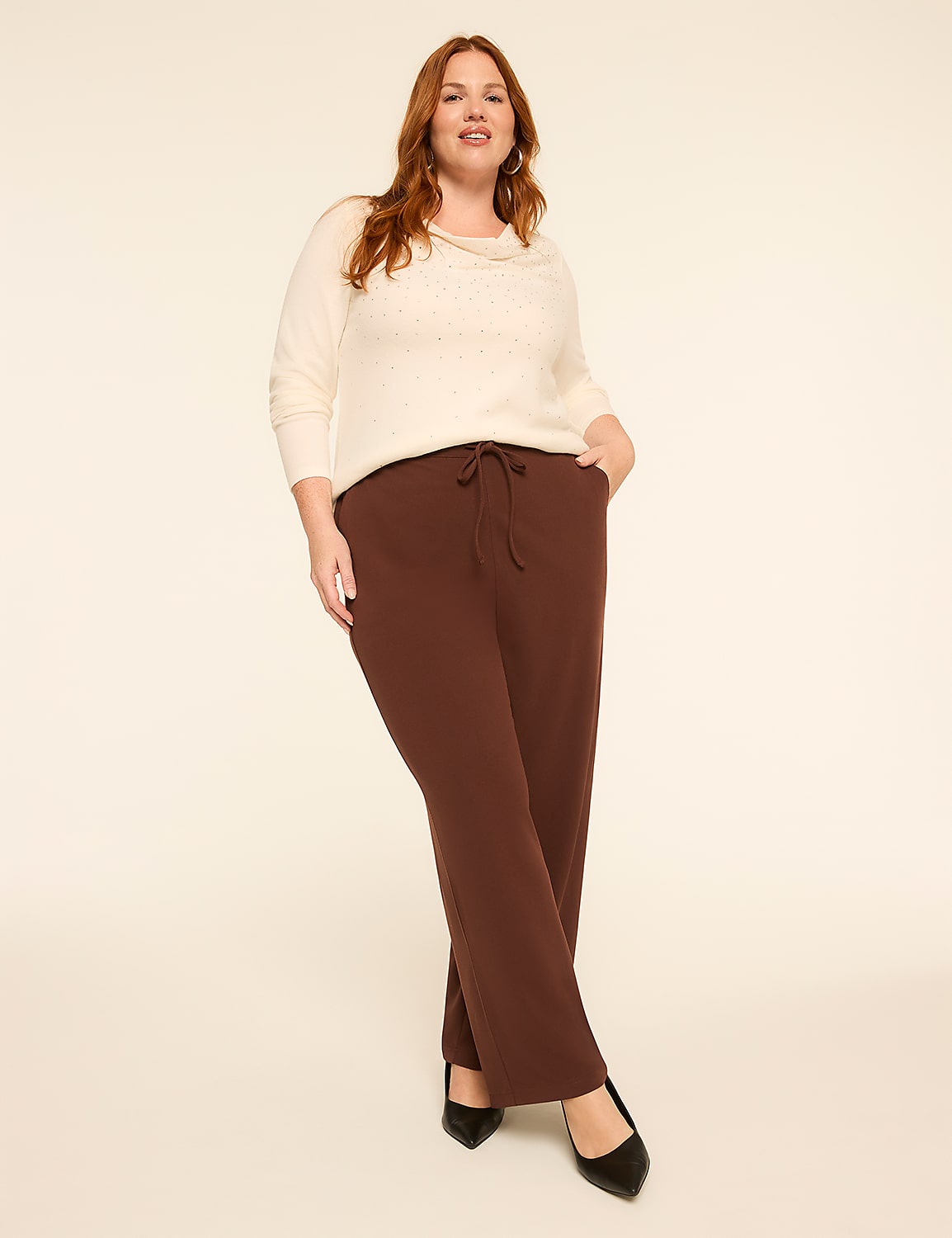 A woman in a cream sweater and brown pants stands against a plain, light-colored background. Product Image 3
