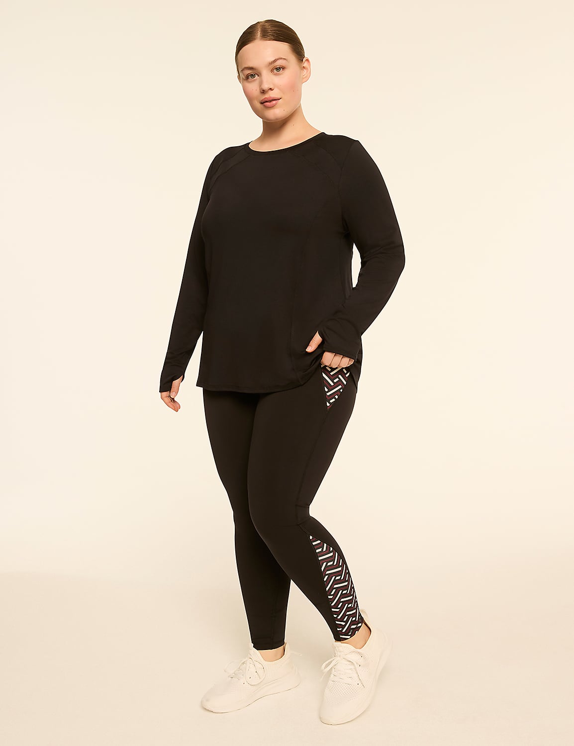 A woman in a black long-sleeved top and leggings with a geometric pattern on the lower leg stands against a plain, light-colored background. Product Image 3