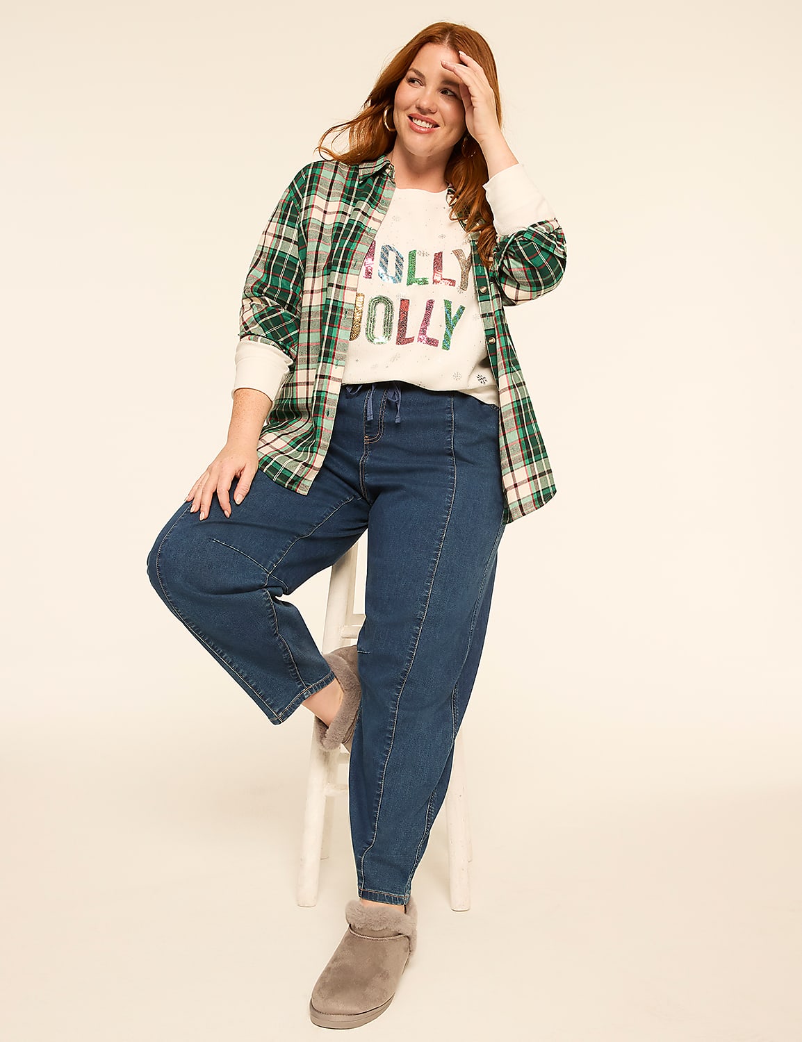 A smiling woman in a festive sweater and jeans sits on a stool against a plain, light background. Product Image 3