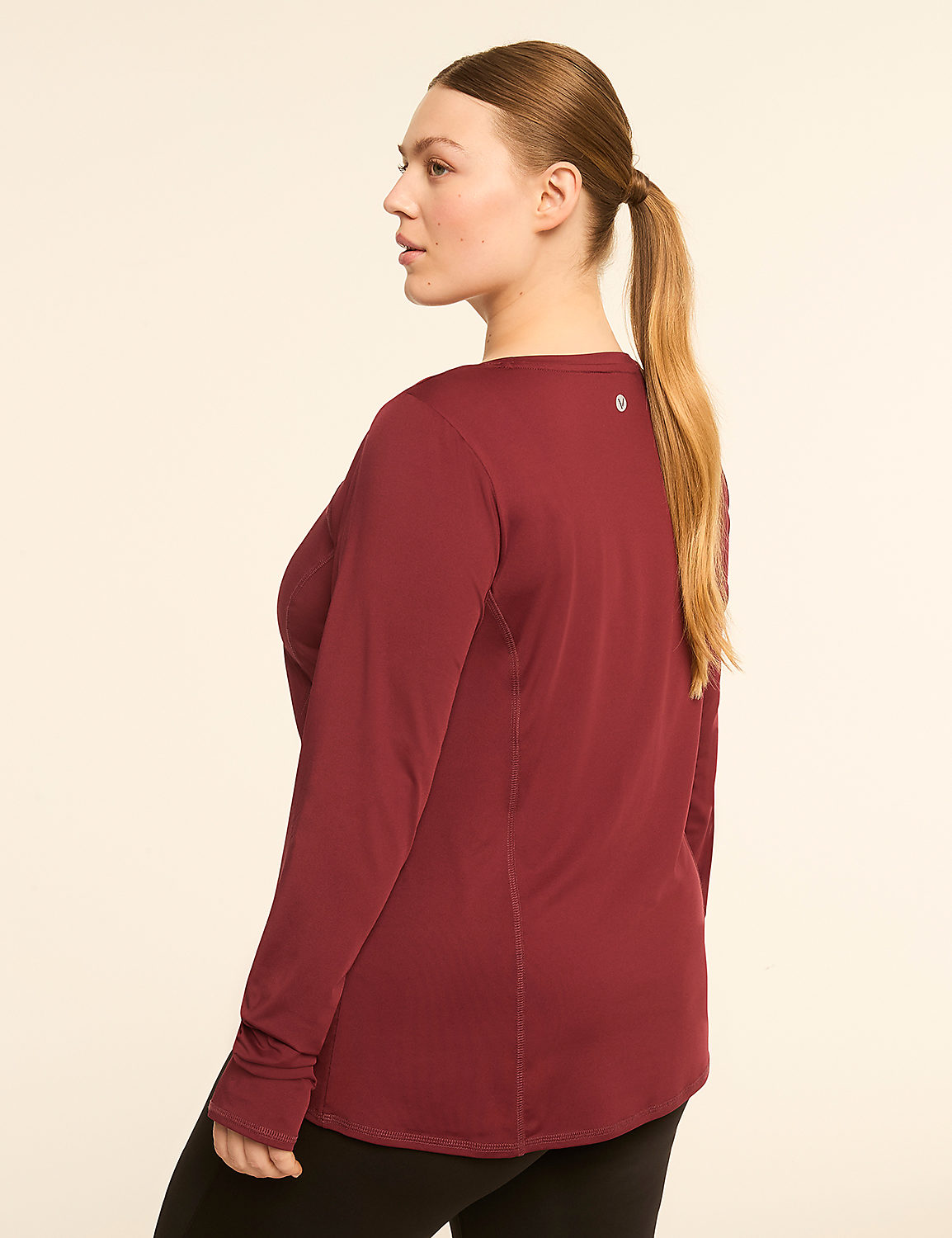 A woman in a maroon long-sleeved shirt and black leggings stands against a plain, light-colored background. Product Image 2