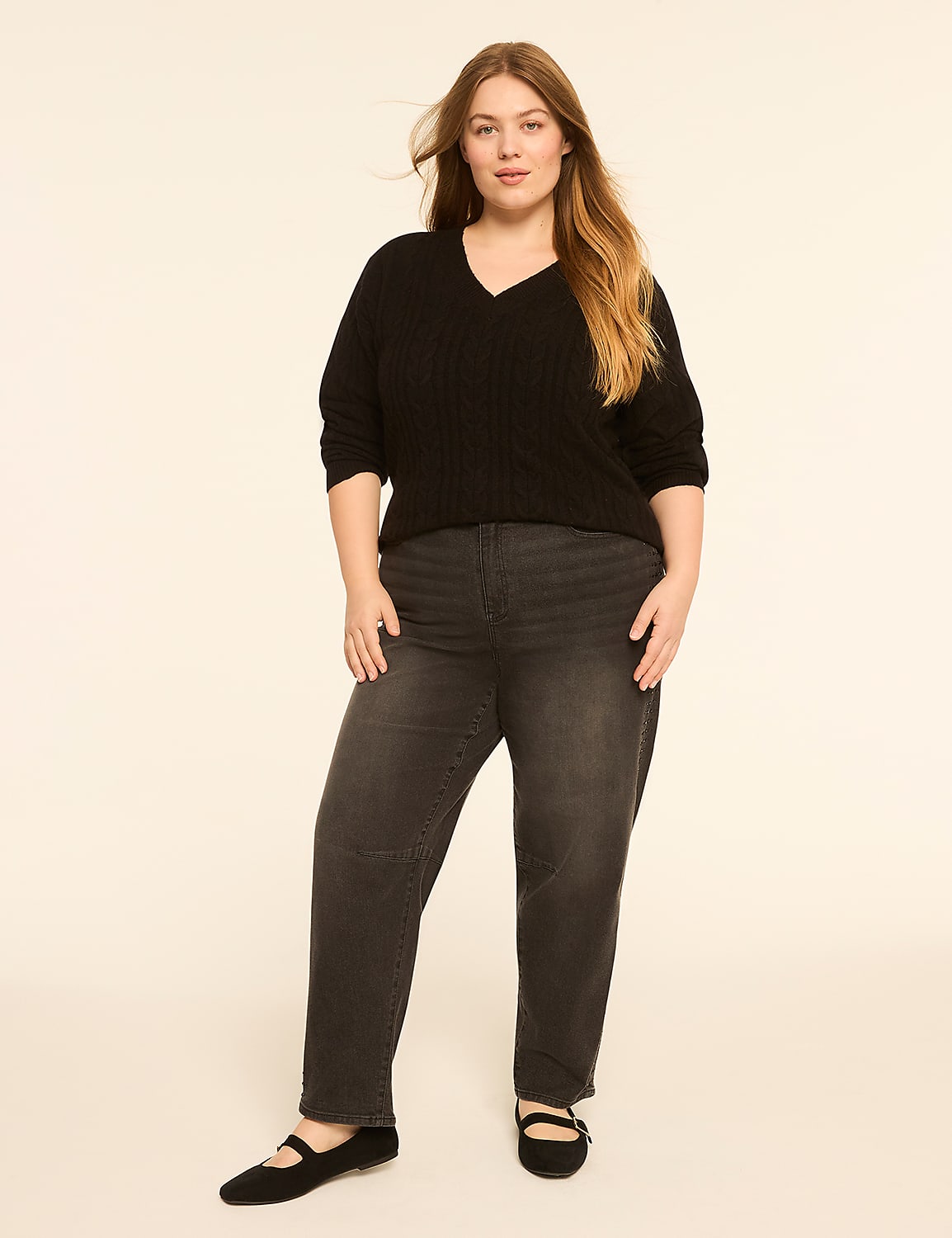 A woman in a black sweater and gray jeans stands against a plain, light-colored background. Product Image 3