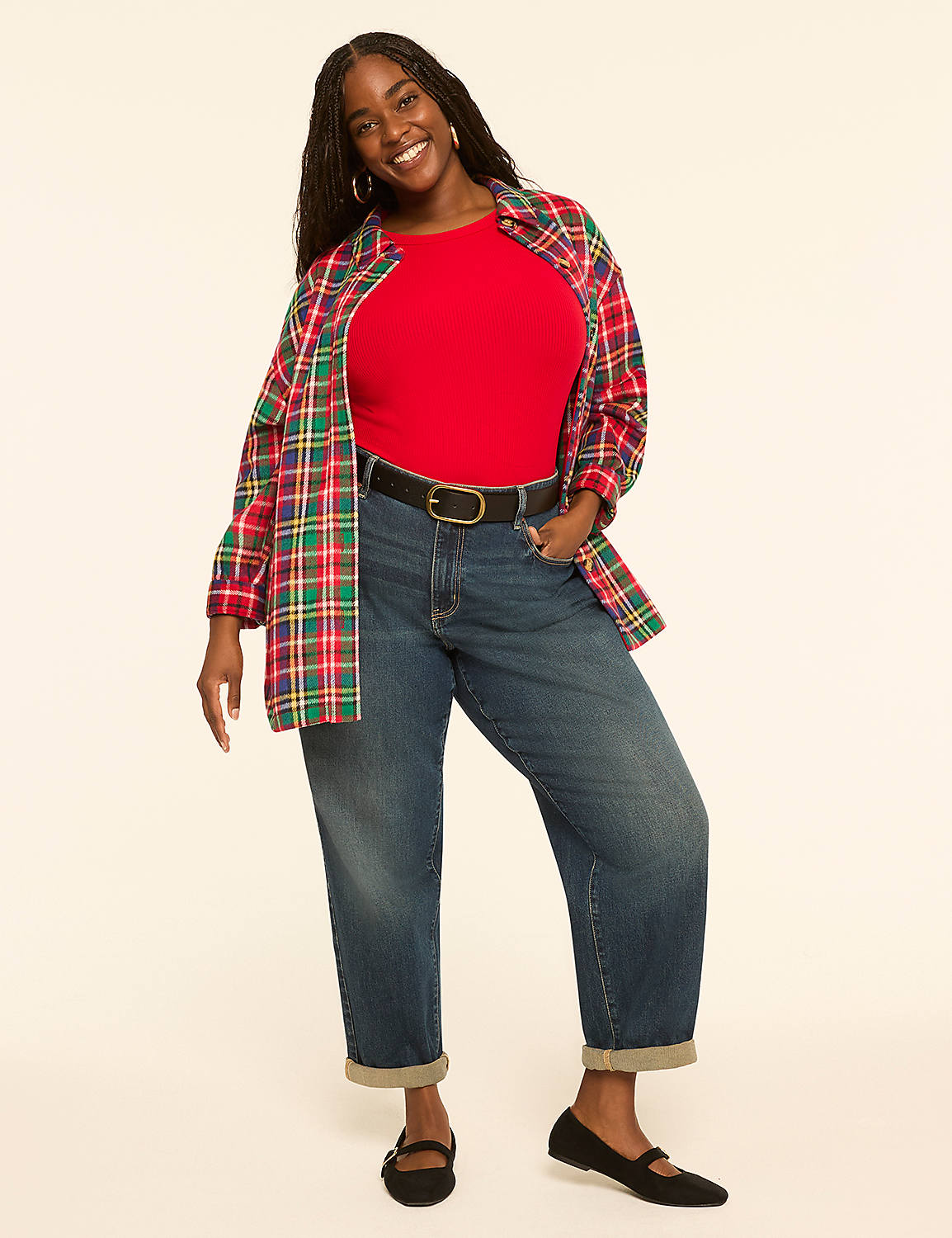 A smiling woman in a red shirt, open plaid shirt, and cuffed jeans stands against a plain, light-colored background. Product Image 3