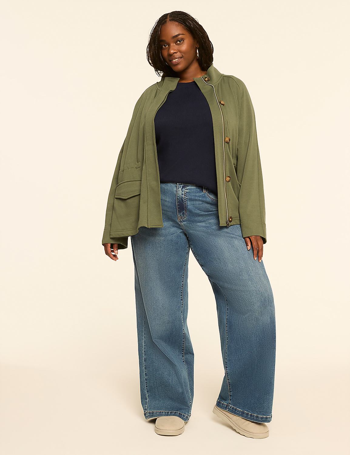 A woman in a green jacket and blue jeans stands against a plain, light-colored background. Product Image 3