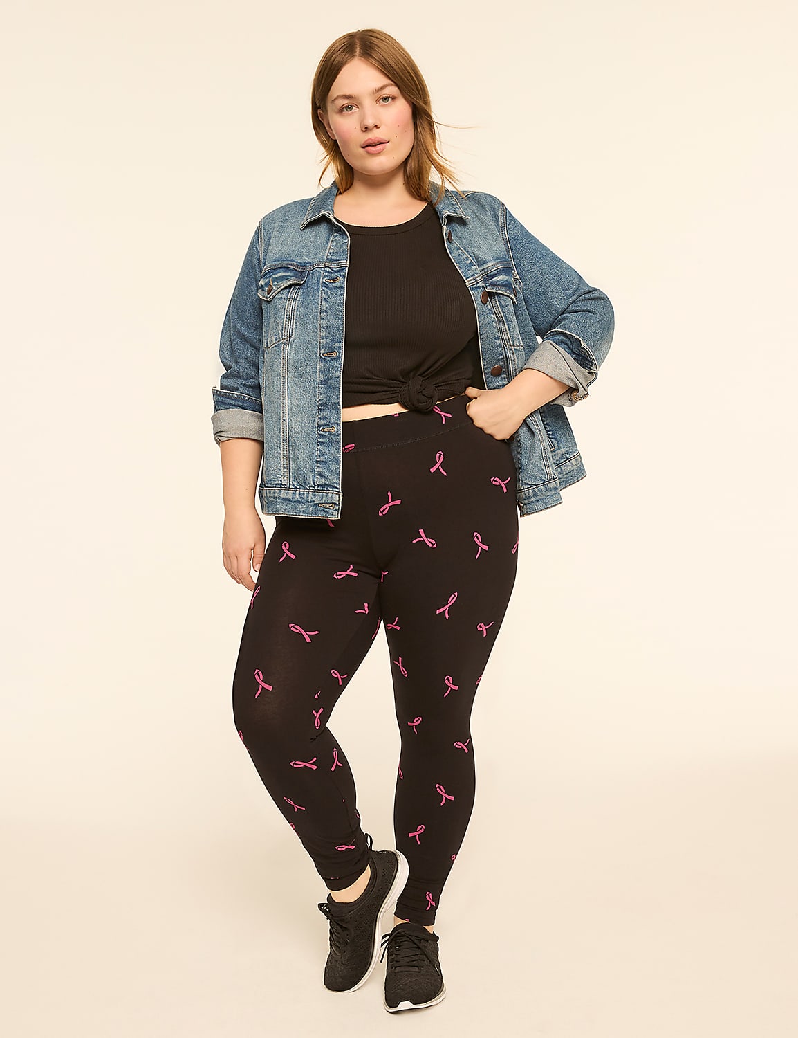 A woman in a denim jacket and black leggings with pink ribbon patterns stands against a plain, light-colored background. Product Image 3