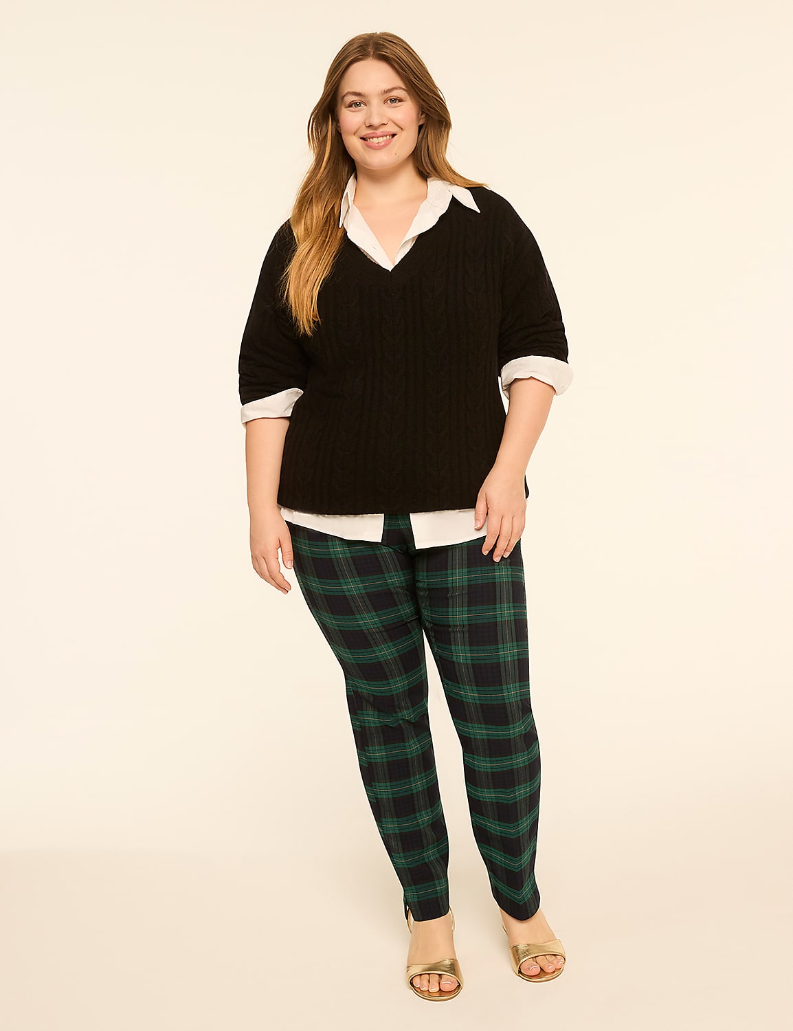 A smiling woman in a black sweater, white shirt, and plaid pants stands against a plain, light-colored background. Product Image 3