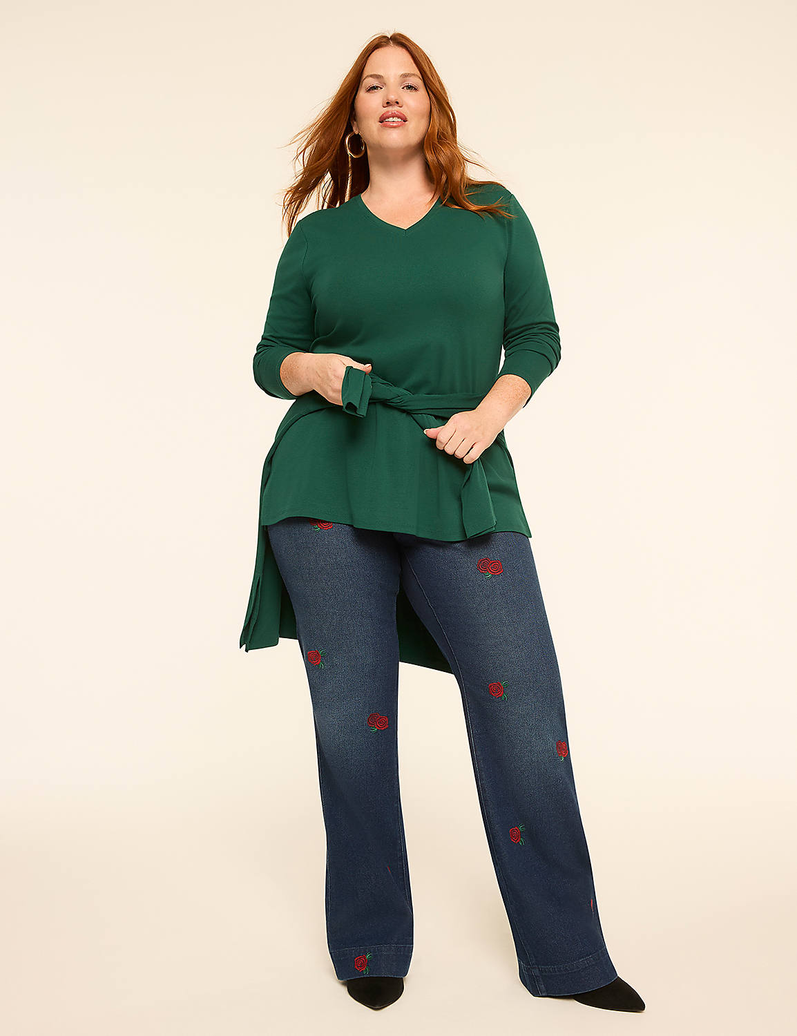 A woman in a green tunic and embroidered jeans stands against a plain, light-colored background. Product Image 3