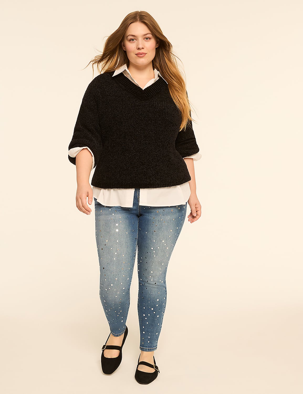 A woman in a black sweater and embellished jeans walks against a plain, light-colored background. Product Image 3