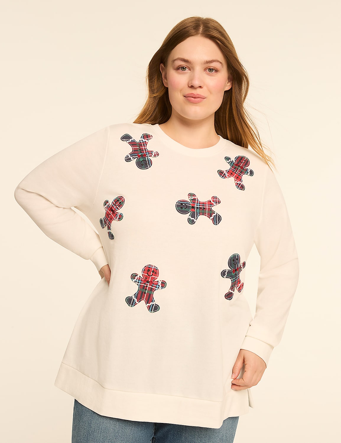 A woman in a cream-colored sweatshirt adorned with plaid gingerbread men stands against a plain, light background. Product Image 1