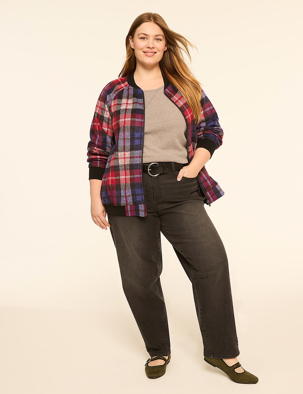 A smiling woman in a plaid bomber jacket and dark jeans stands against a plain, light-colored background. Product Image 3