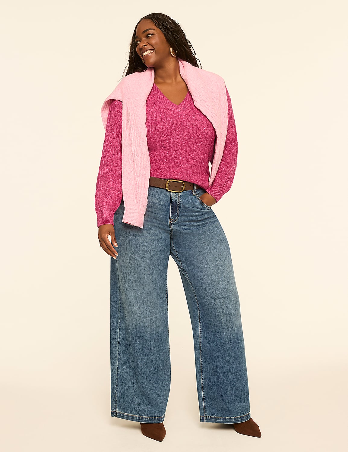A smiling woman in a pink cable-knit sweater and wide-leg jeans stands against a plain, light-colored background. Product Image 3