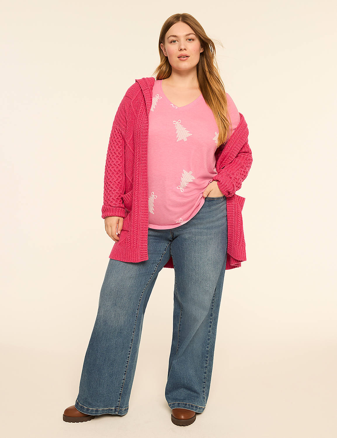 A woman in a pink Christmas tree t-shirt and a chunky pink cardigan stands in front of a plain cream background. Product Image 3